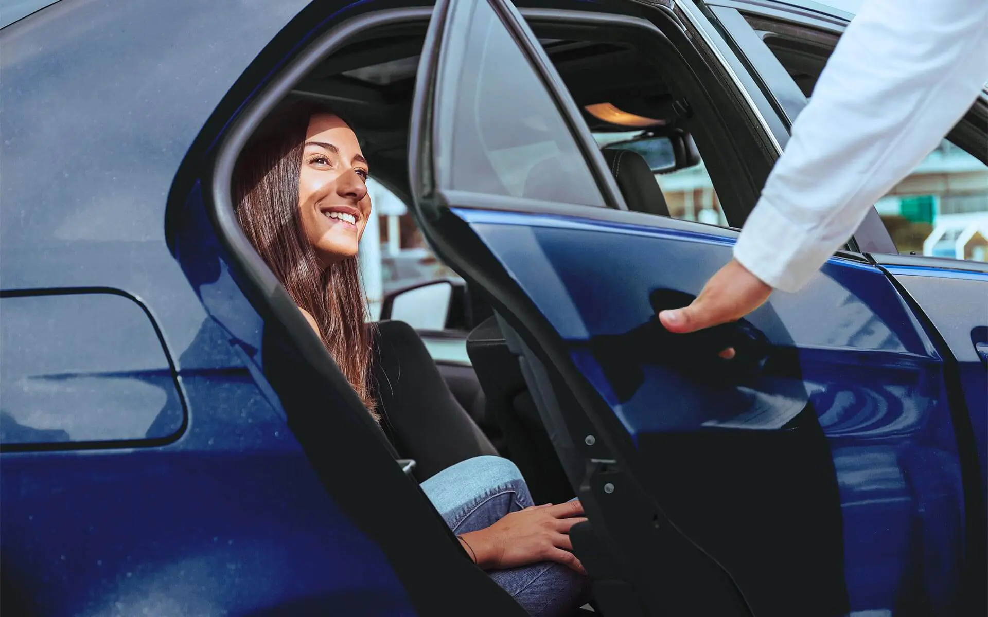 Woman smiling inside a car as door is opened.