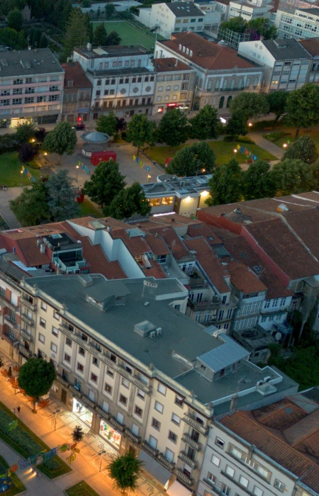 Vista a&eacute;rea de edif&iacute;cios e parque &agrave; noite com luzes acesas.