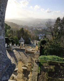 Escadaria em jardim com vista da cidade ao fundo.