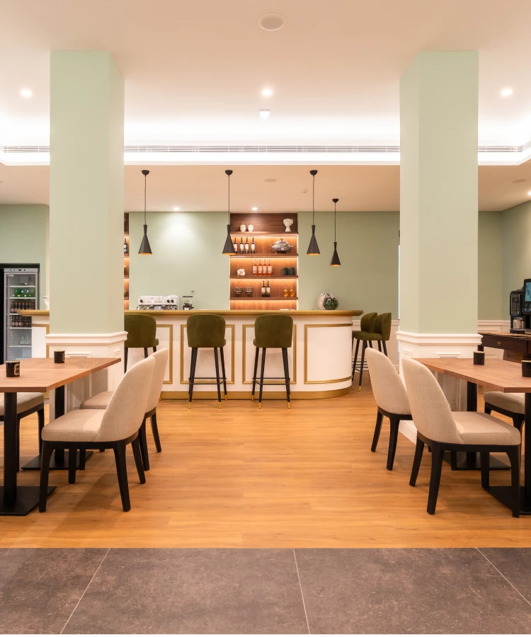 Sala de estar com balc&atilde;o de bar, mesas e cadeiras, ilumina&ccedil;&atilde;o moderna.