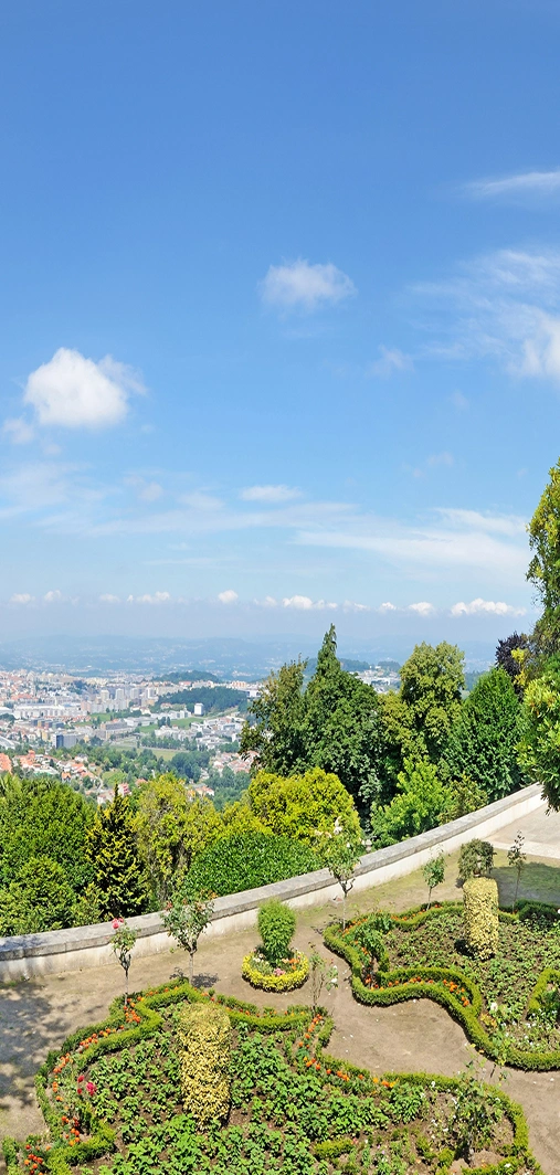 Vista panor&acirc;mica de cidade e jardins com c&eacute;u azul e nuvens.