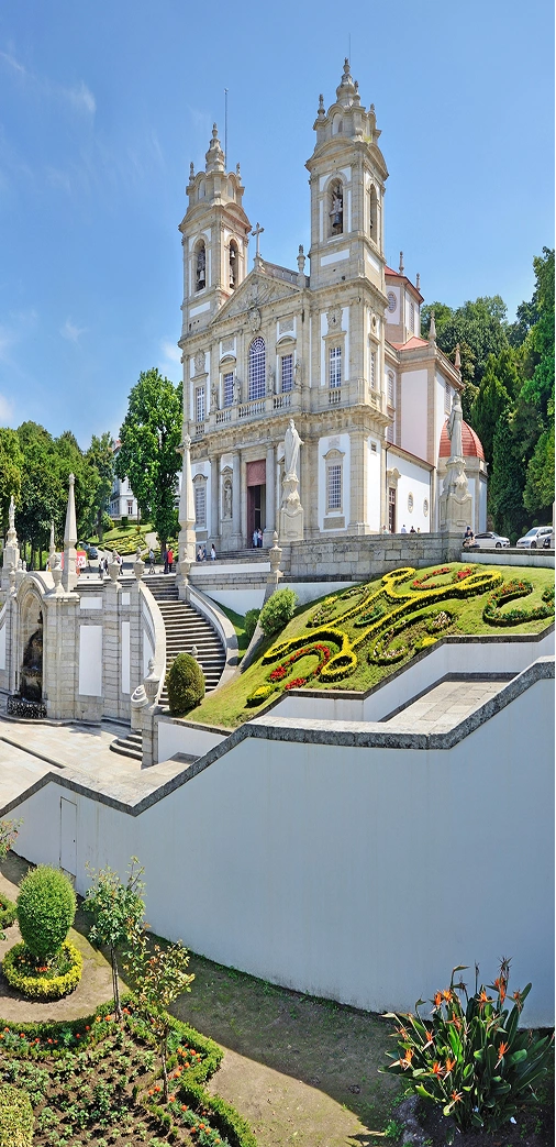 Igreja com fachada barroca e jardins bem cuidados ao redor.