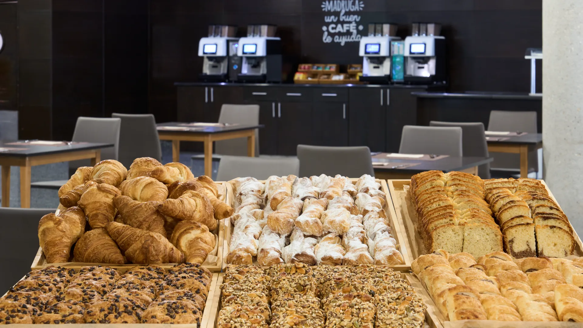 Mesa con variedad de panes en cafeter&iacute;a moderna.