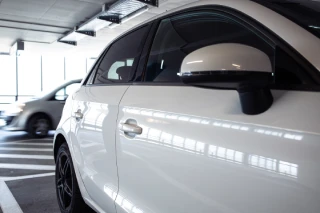 Autos en estacionamiento techado iluminado por luz natural.