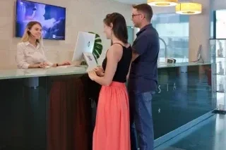 Personas en recepci&oacute;n de un hotel, siendo atendidas por una recepcionista.
