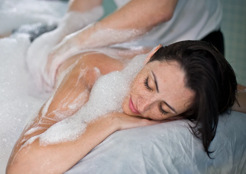 Persona recibiendo masaje de espuma en spa, relajada y disfrutando.