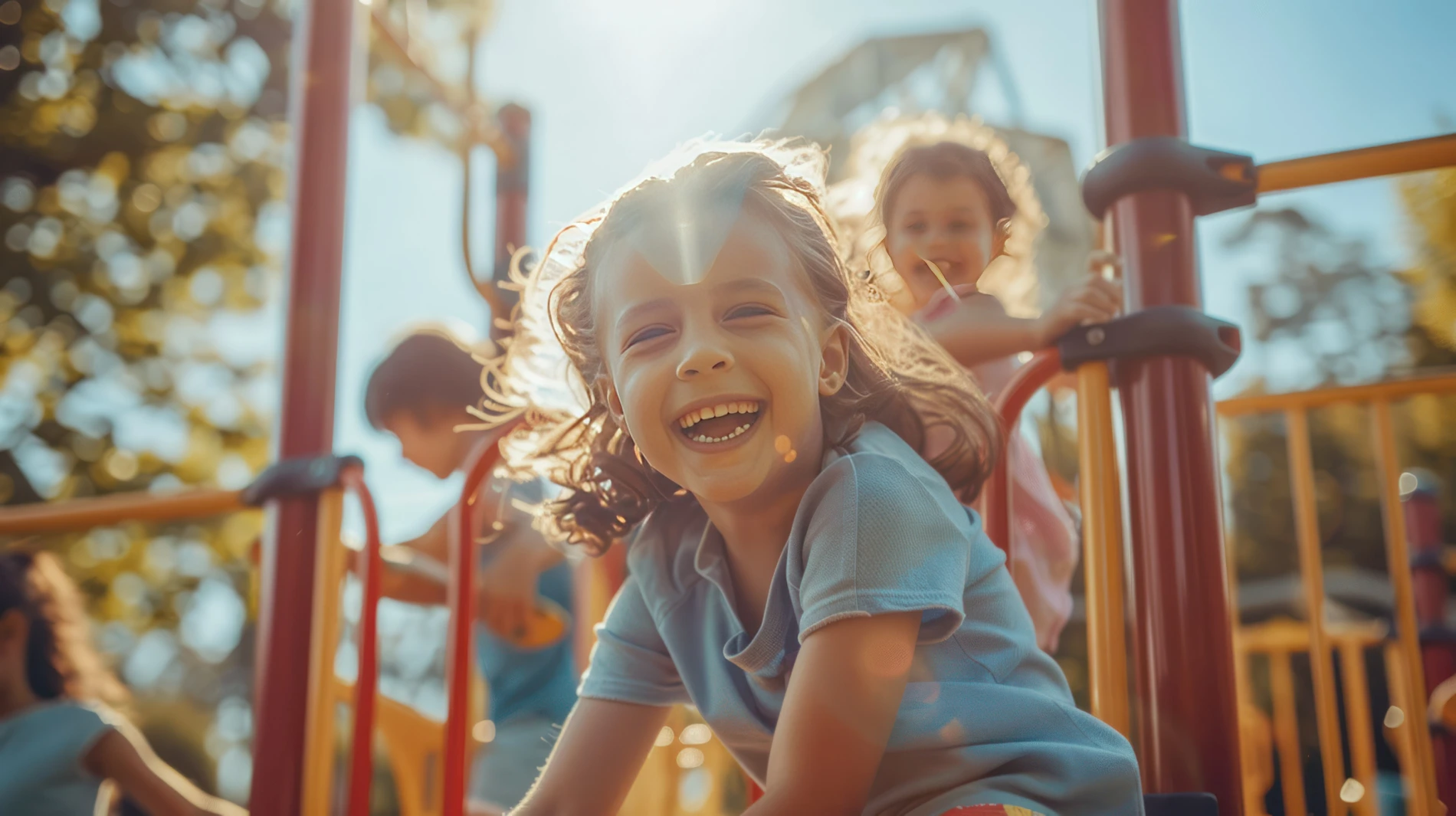 Crian&ccedil;as brincando e sorrindo em um parquinho iluminado pelo sol.