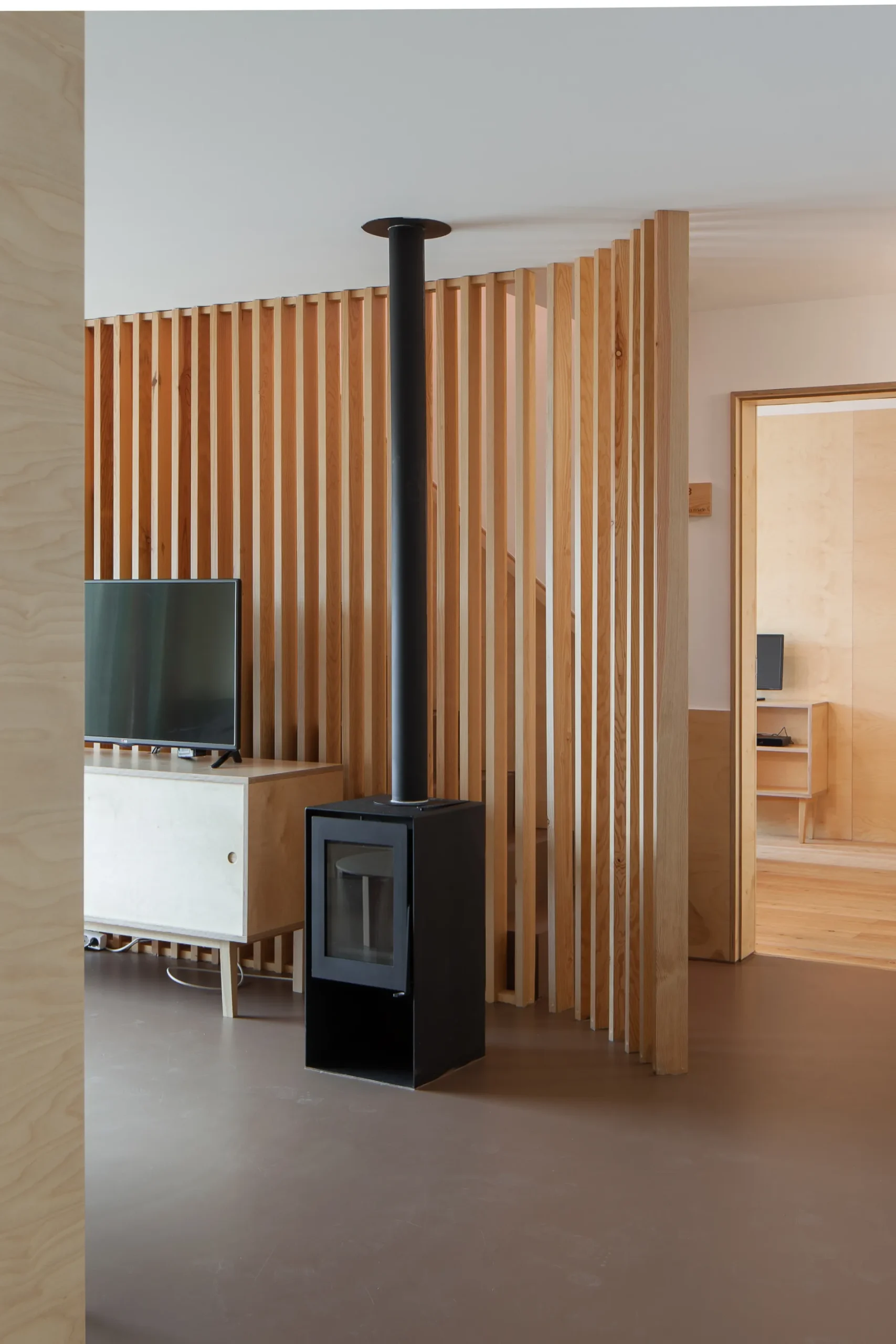 Sala moderna com lareira preta e divis&oacute;ria de madeira.