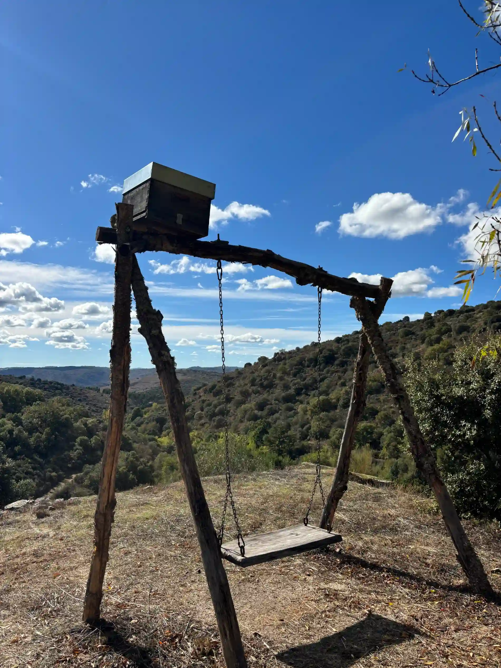 Baloi&ccedil;o de madeira com uma caixa em cima, em uma colina sob c&eacute;u azul e nuvens.