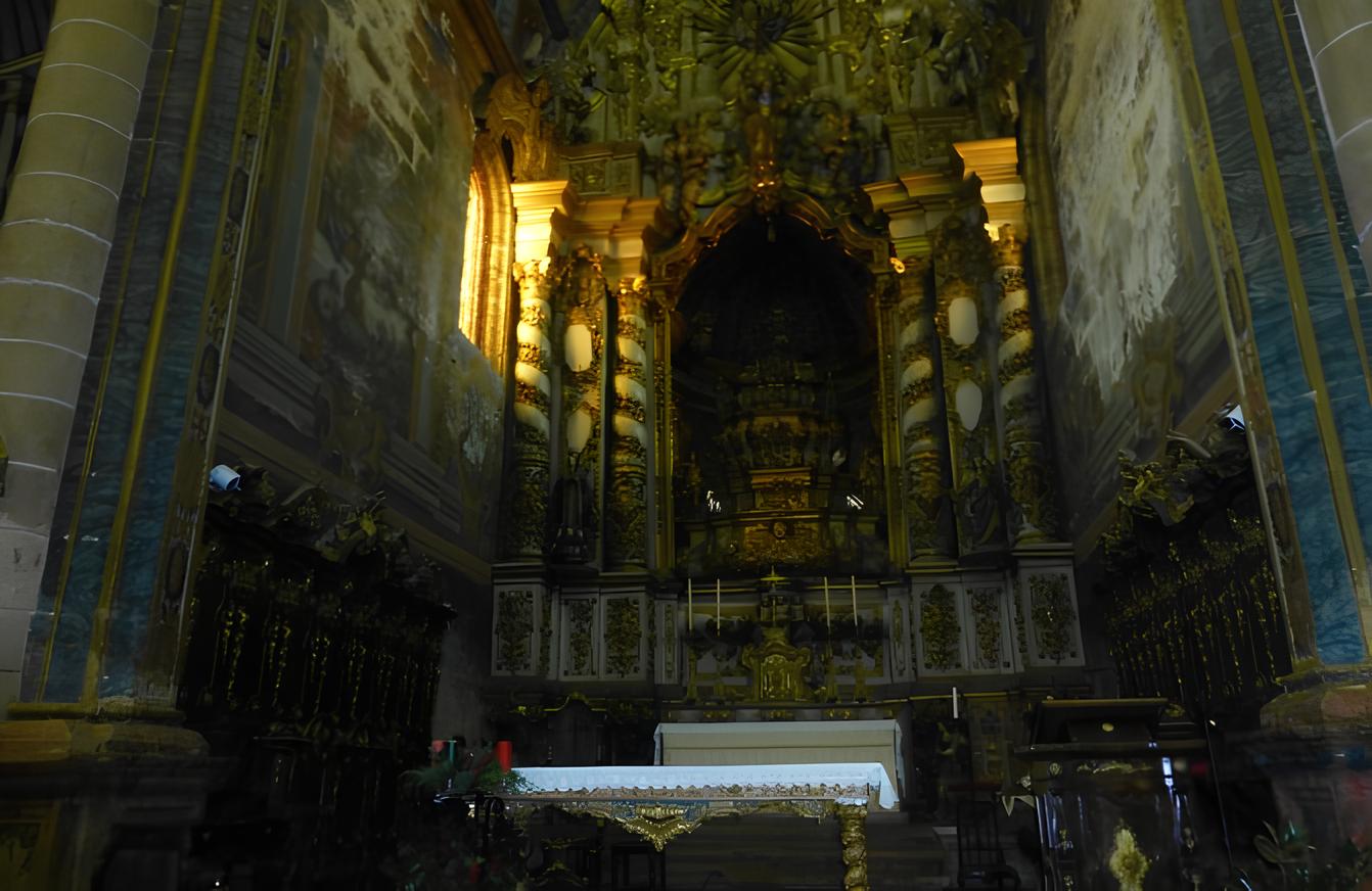 Altar de igreja barroca ornamentada, com colunas e detalhes dourados iluminados por luz solar.