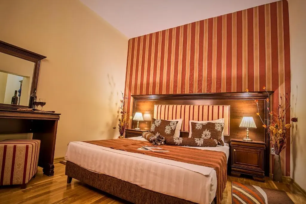 Cozy bedroom with striped wallpaper, wooden furniture, and warm lighting.