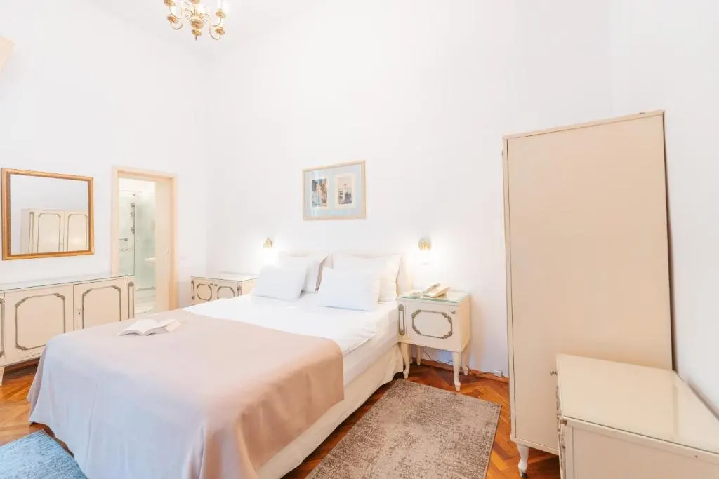 Bright bedroom with white furniture and a neatly made bed.