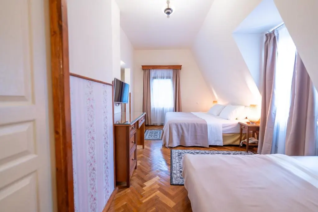 Cozy bedroom with two beds, TV, and curtains in soft lighting.