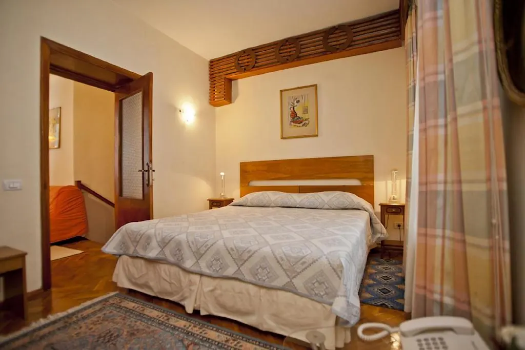 Cozy bedroom with a patterned bedspread and warm lighting.