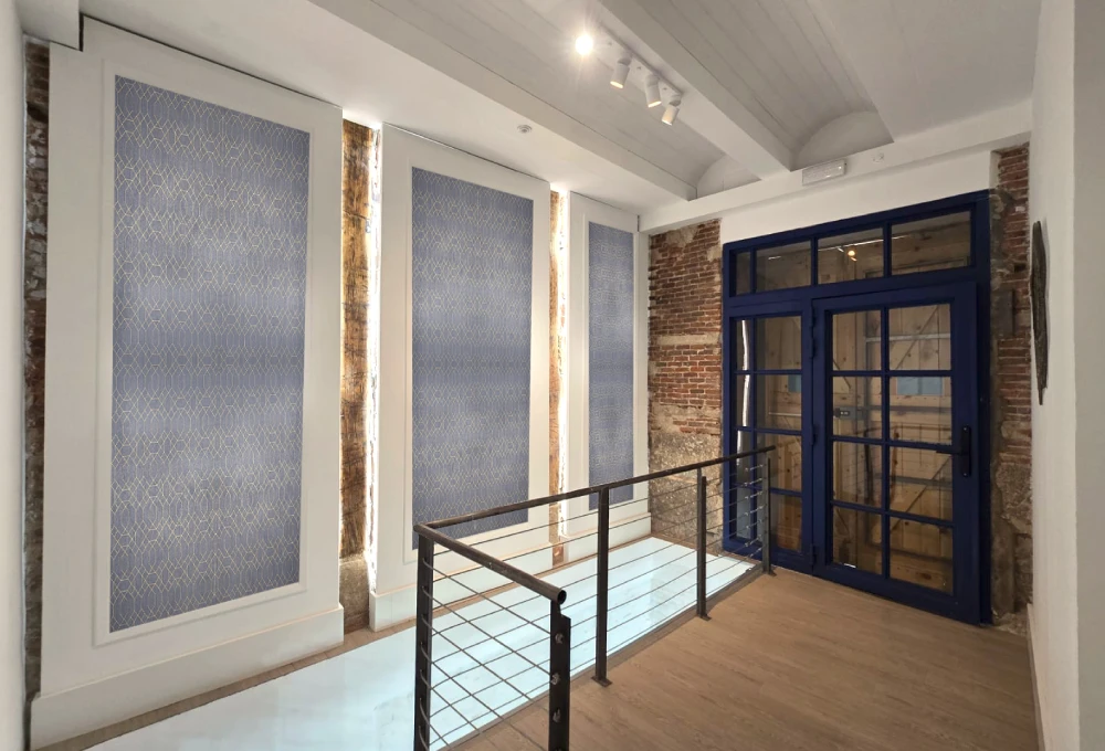 Espacio interior con paredes de ladrillo y ventanas con marco azul.