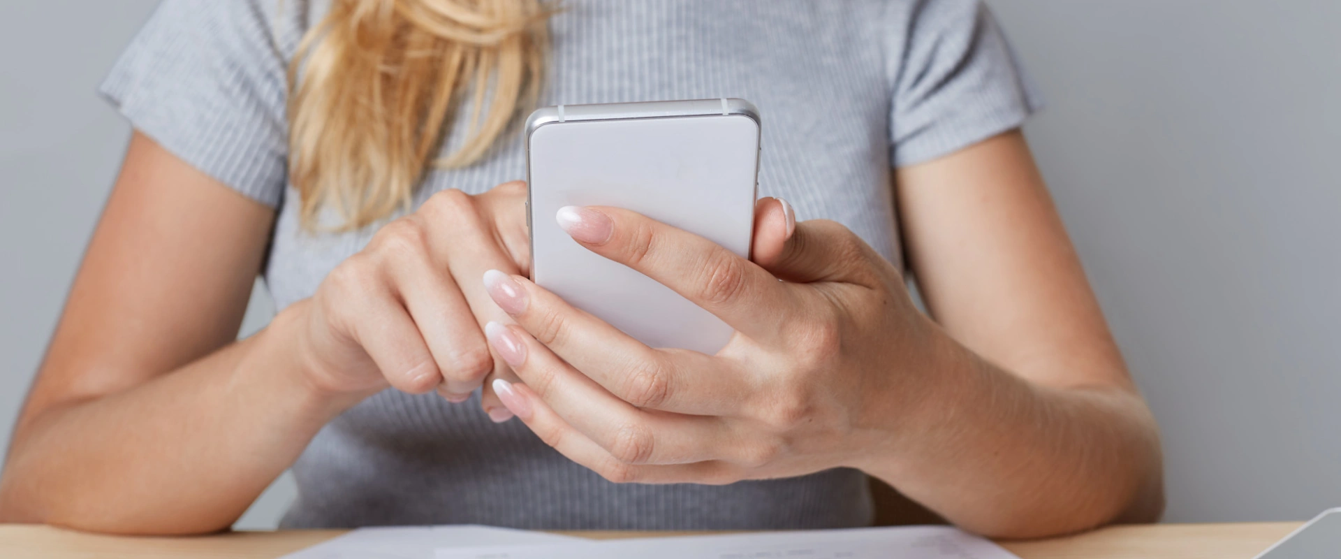 Mujer usando un smartphone mientras est&aacute; sentada en una mesa.