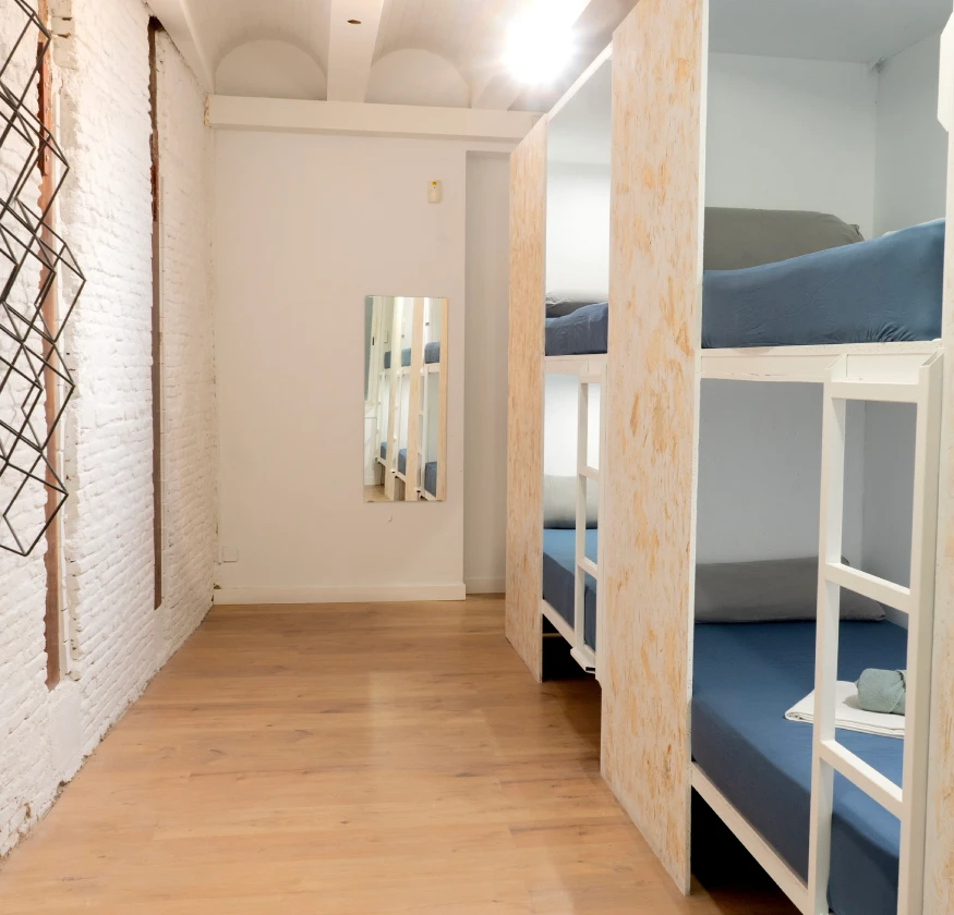 Habitaci&oacute;n con literas de madera, suelo de parquet y pared de ladrillo blanco.