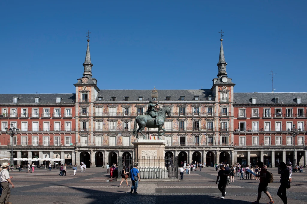Plaza Mayor de Madrid con estatua ecuestre y gente paseando.