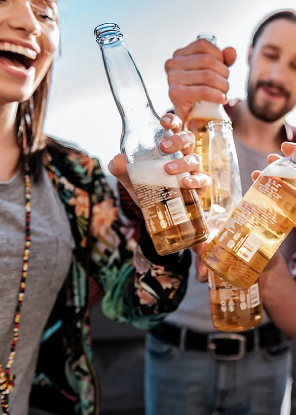 Personas brindando con botellas de cerveza en un ambiente al aire libre.