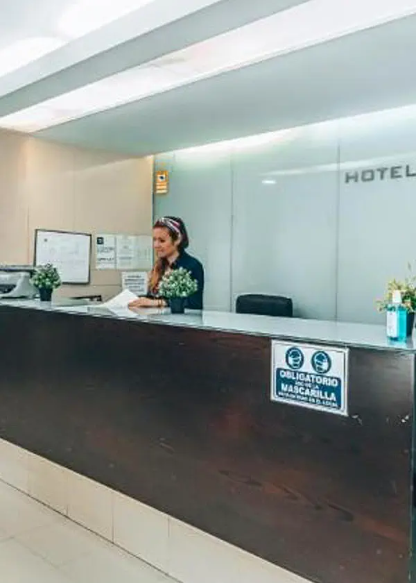 Recepci&oacute;n de hotel. La recepcionista est&aacute; leyendo un documento.