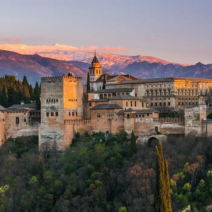 La Alhambra al atardecer con monta&ntilde;as nevadas al fondo.