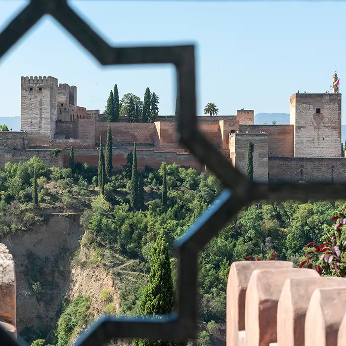 Vista de una fortaleza entre un enrejado con &aacute;rboles verdes al frente.