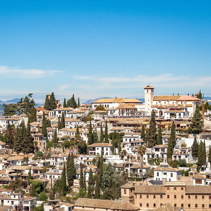 Vista panor&aacute;mica de un barrio con casas blancas y una iglesia en el fondo.