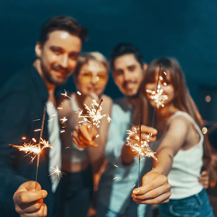 Grupo de personas sosteniendo bengalas encendidas en una noche festiva.
