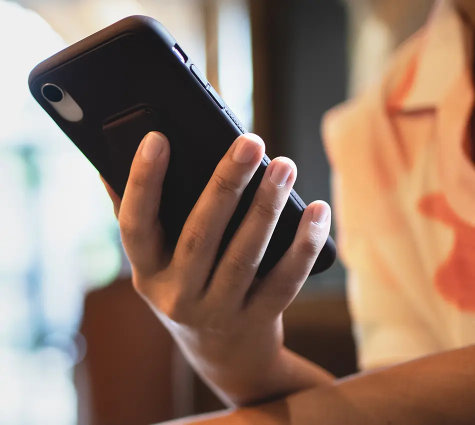 Mano sosteniendo un smartphone en un ambiente interior.