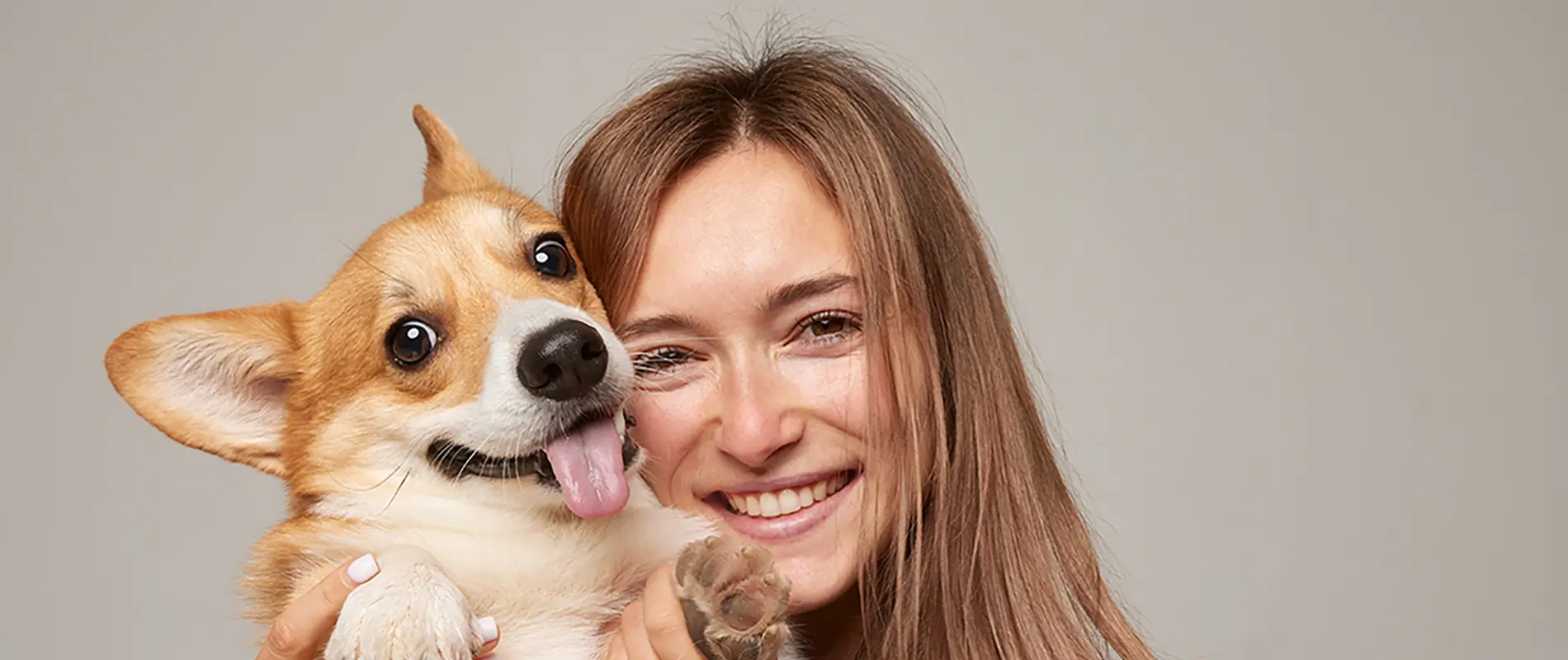 Persona sonriendo con un perro en brazos con expresi&oacute;n alegre.