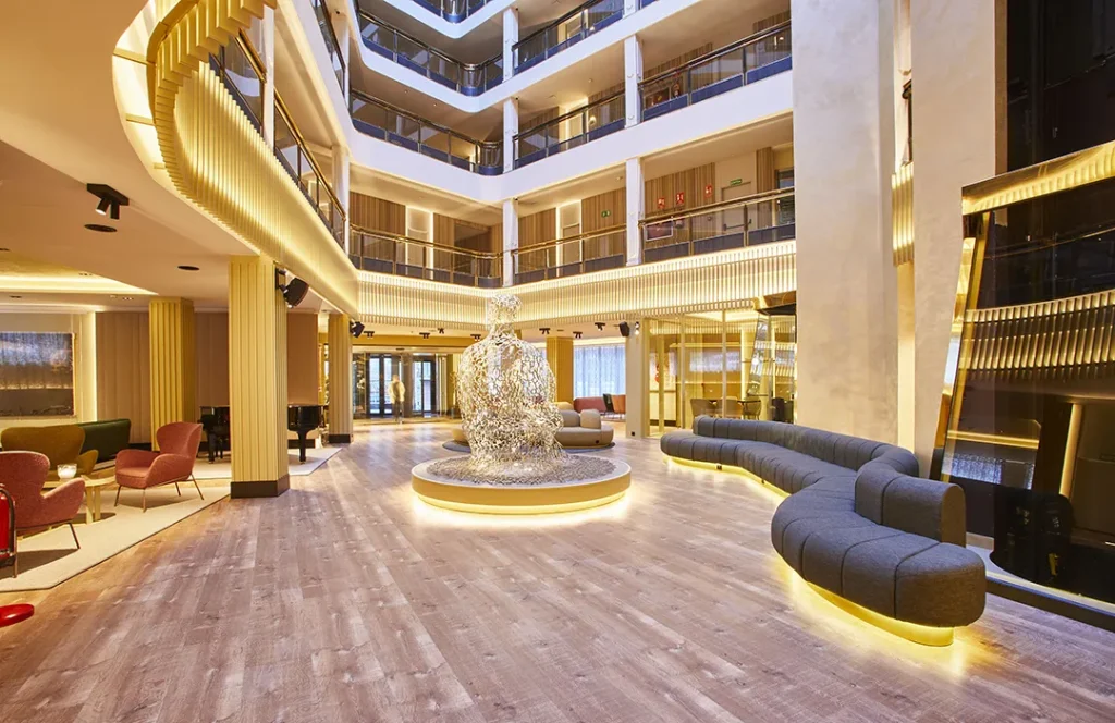 Vest&iacute;bulo moderno con escultura iluminada y asientos elegantes.