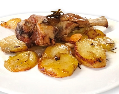 Pierna de cordero al horno con rodajas de patata doradas en un plato.