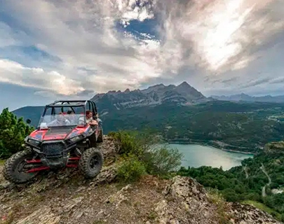 Veh&iacute;culo todoterreno en monta&ntilde;a con lago y monta&ntilde;as al fondo.