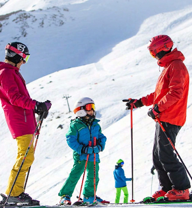 Personas esquiando en la nieve, vistiendo ropa de colores brillantes.