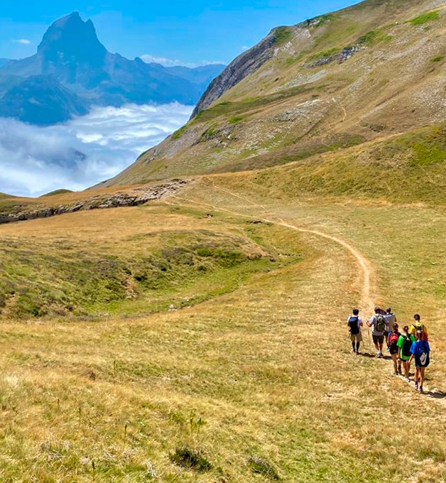 Grupo de excursionistas caminando en un sendero monta&ntilde;oso con niebla.