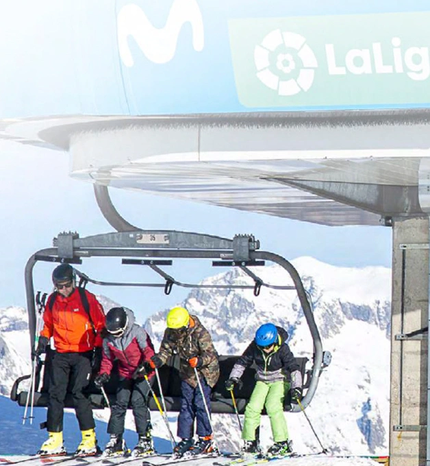 Esquiadores bajando de un telesilla en una estaci&oacute;n de esqu&iacute; nevada.
