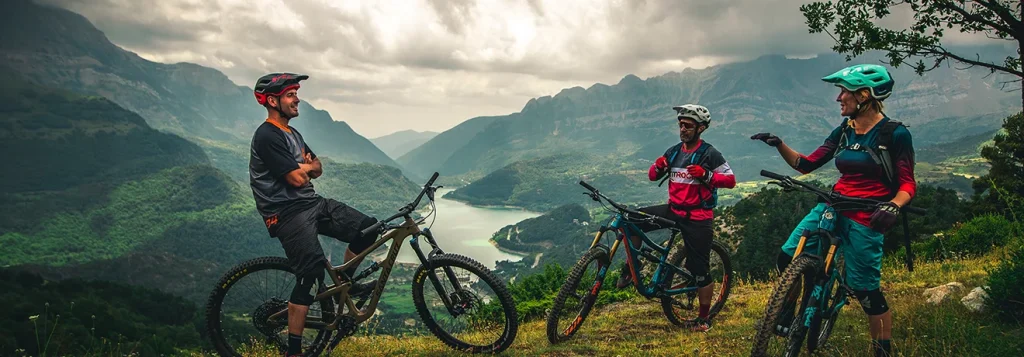 Tres ciclistas conversan en un mirador con monta&ntilde;as y un lago de fondo.