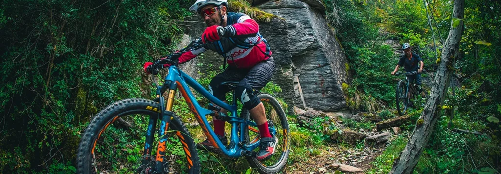 Ciclistas de monta&ntilde;a recorriendo un sendero rodeado de vegetaci&oacute;n.
