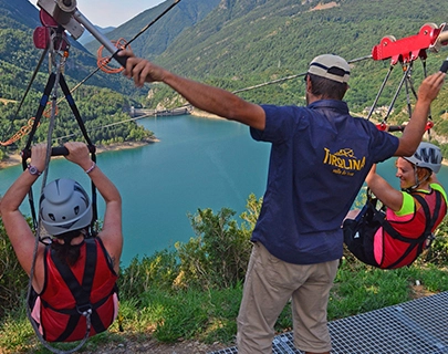 Personas se preparan para lanzarse en tirolesa sobre un lago azul y monta&ntilde;as.