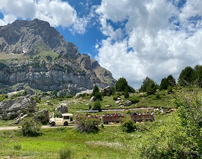 Autob&uacute;s en un paisaje monta&ntilde;oso con cielo azul y nubes.