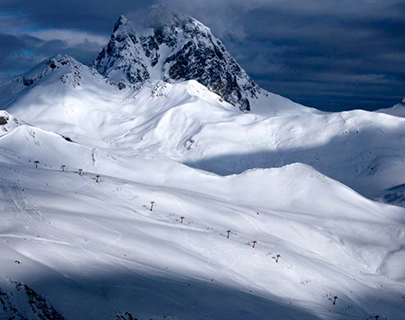 Monta&ntilde;a nevada iluminada d&eacute;bilmente por el sol con telesillas en el fondo.