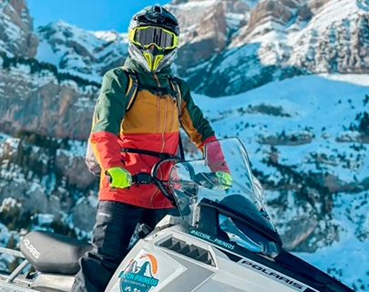 Persona en moto de nieve en paisaje monta&ntilde;oso nevado.