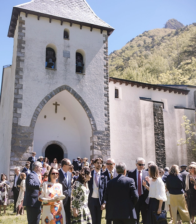 Personas reunidas frente a una iglesia en un d&iacute;a soleado en la monta&ntilde;a.