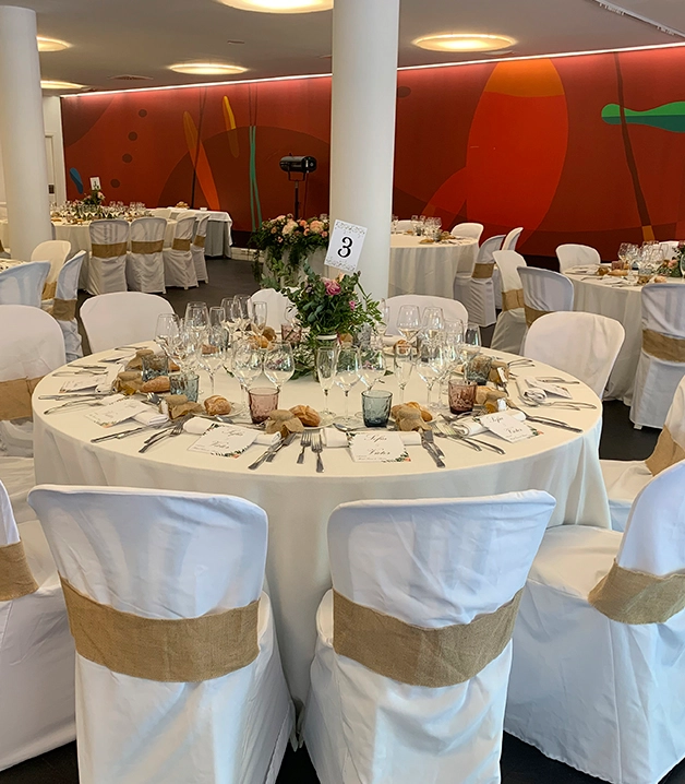 Mesa de banquete elegantemente decorada con platos y copas de cristal.