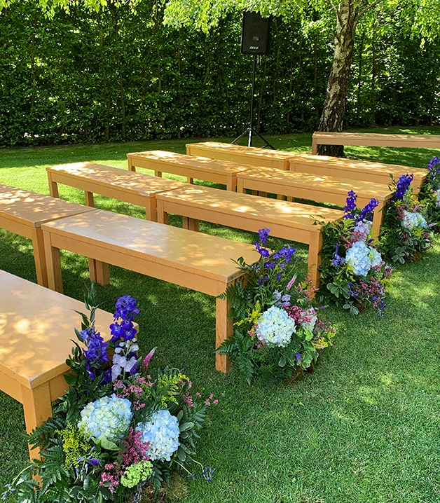 Bancos de madera con flores coloridas en un jard&iacute;n soleado.