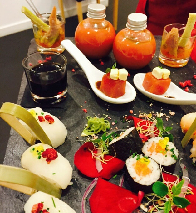 Plato de sushi variado con salsas y decoraciones coloridas.