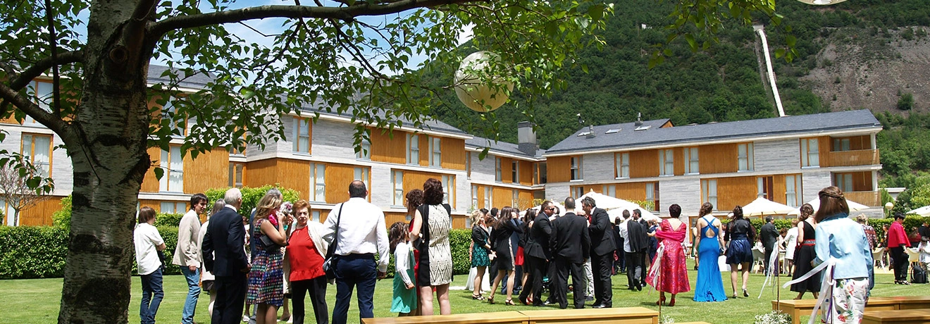 Personas en evento al aire libre frente a un edificio de madera y piedra.