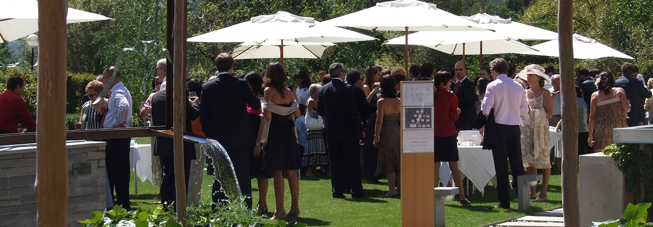 Personas reunidas en un evento al aire libre bajo sombrillas blancas.