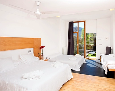 Habitaci&oacute;n luminosa con dos camas dobles, balc&oacute;n y vistas al exterior.