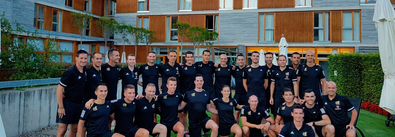 Grupo de personas con uniforme negro posando frente a edificio moderno.